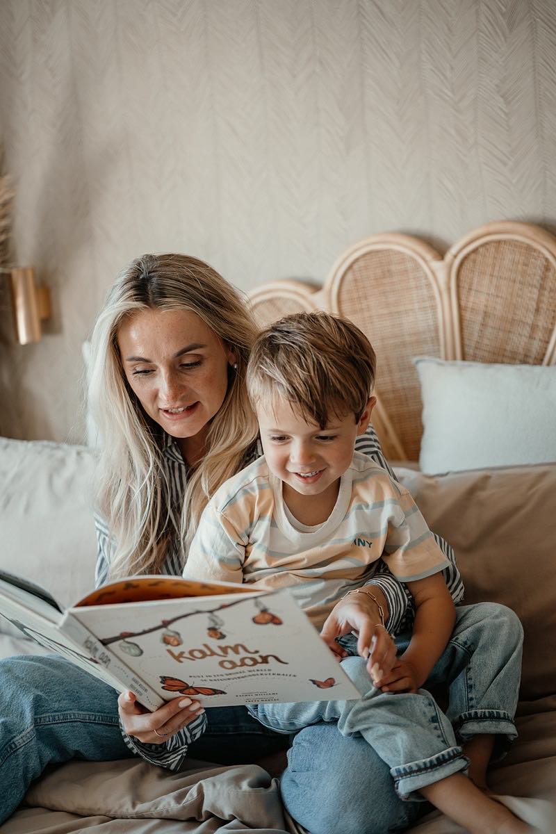 Nanny reading a picture book to a boy on the bed