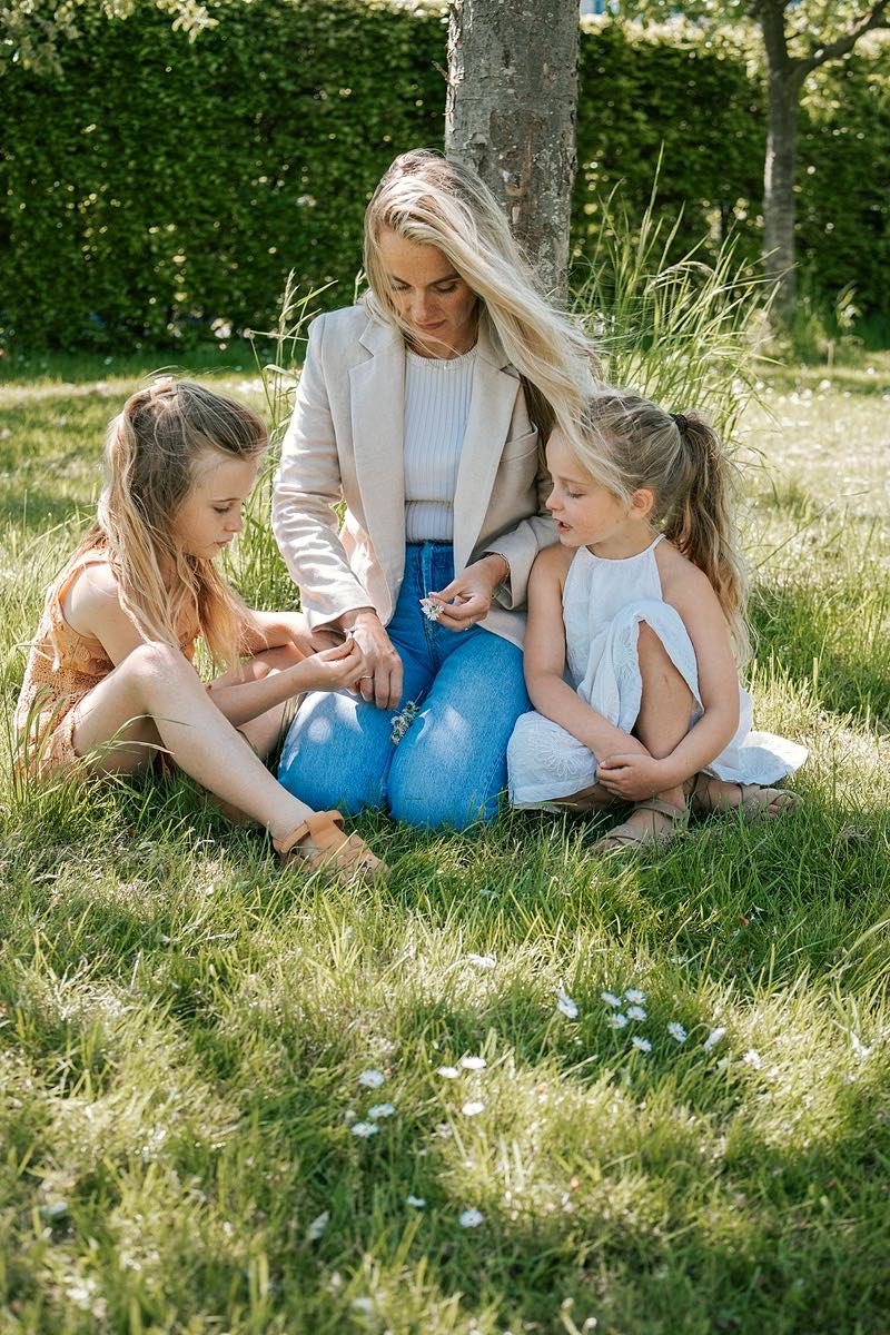 Nanny zit met twee meisjes in het gras